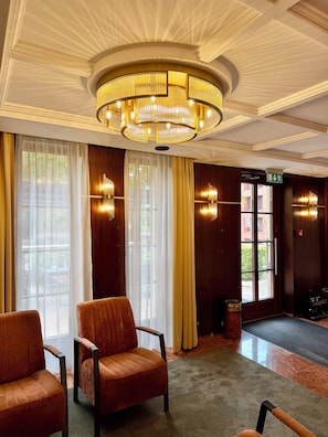 A hotel lobby with a large chandelier, plush seating, and a view of the outdoors through large windows. - Gold Hotel Budapest (Budapest)
