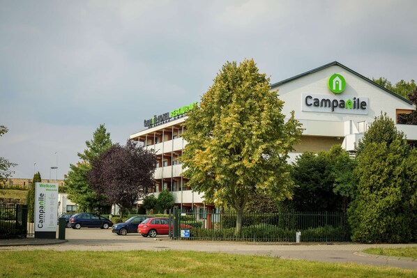 Ein Hotel mit einem Schild auf dem Dach, das "Campanile Welcome" und "Hotel Restaurant" zeigt.
