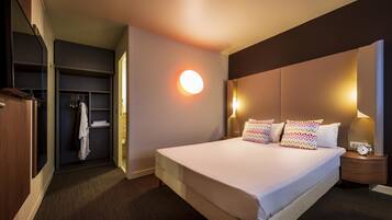 A hotel room with a large bed, bedside lamps, a nightstand, a wardrobe, and a circular wall light.