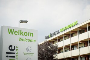 Ein Schild mit der Aufschrift 'Welcome' und 'Kammer 2-3 Personen', das die Zimmerkapazität anzeigt.