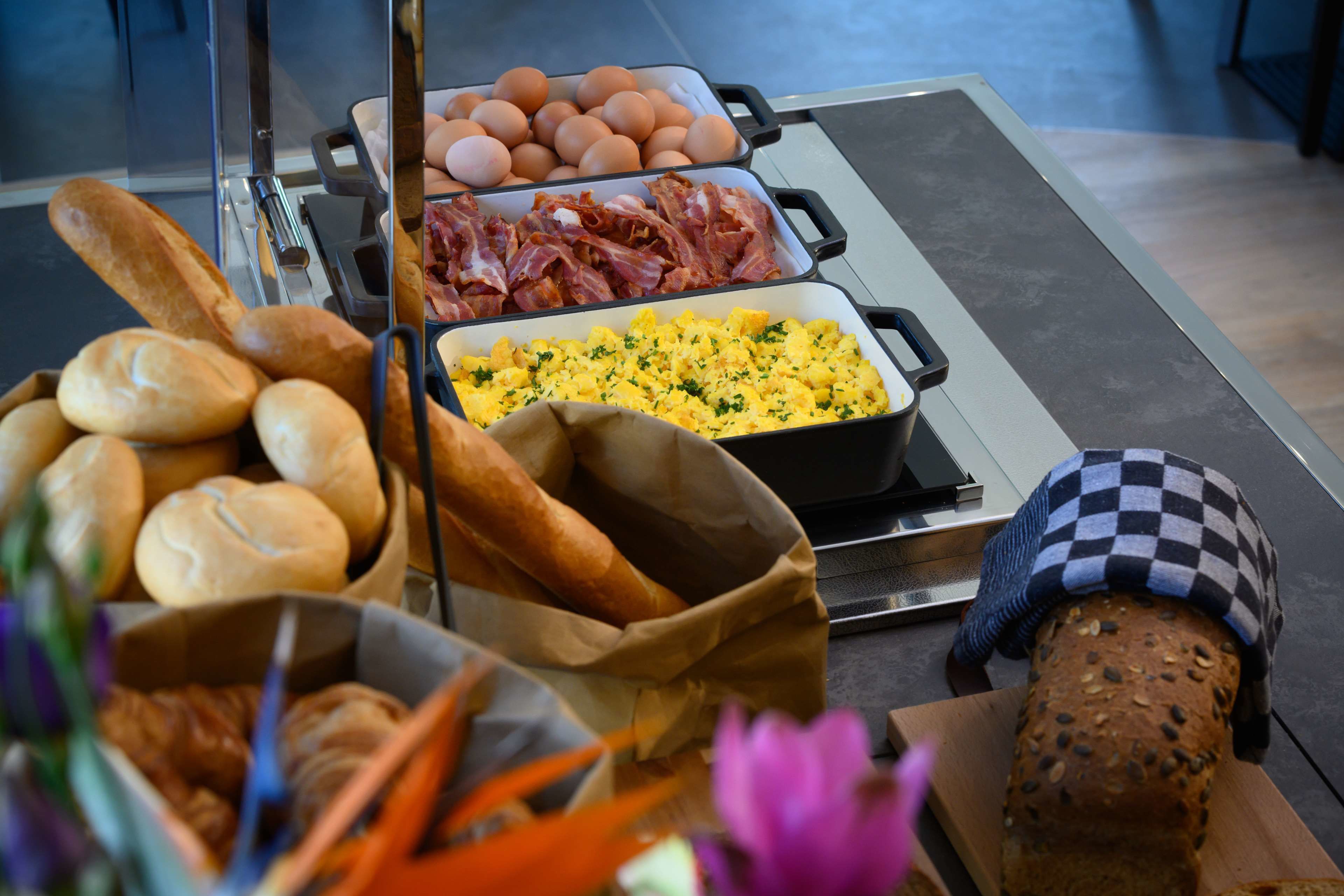A breakfast buffet with bread, eggs, bacon, and scrambled eggs.