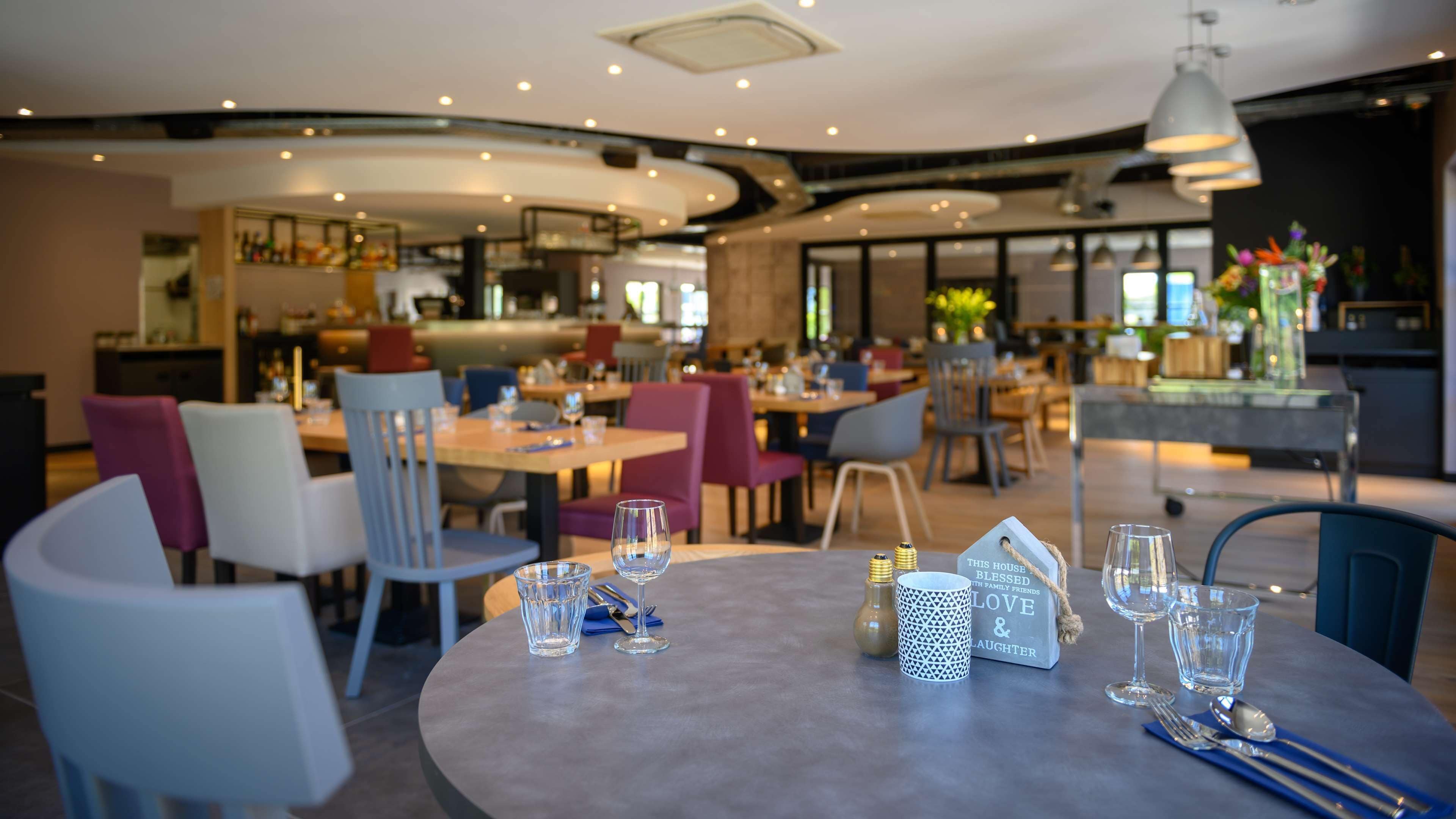 Un restaurante con mesas redondas, sillas y una zona de bar.
