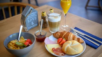 A breakfast setting with a bowl of cereal, a croissant, a plate with ham and cheese, a glass of orange juice, and a sign that reads "House is blessed with family & laughter."
