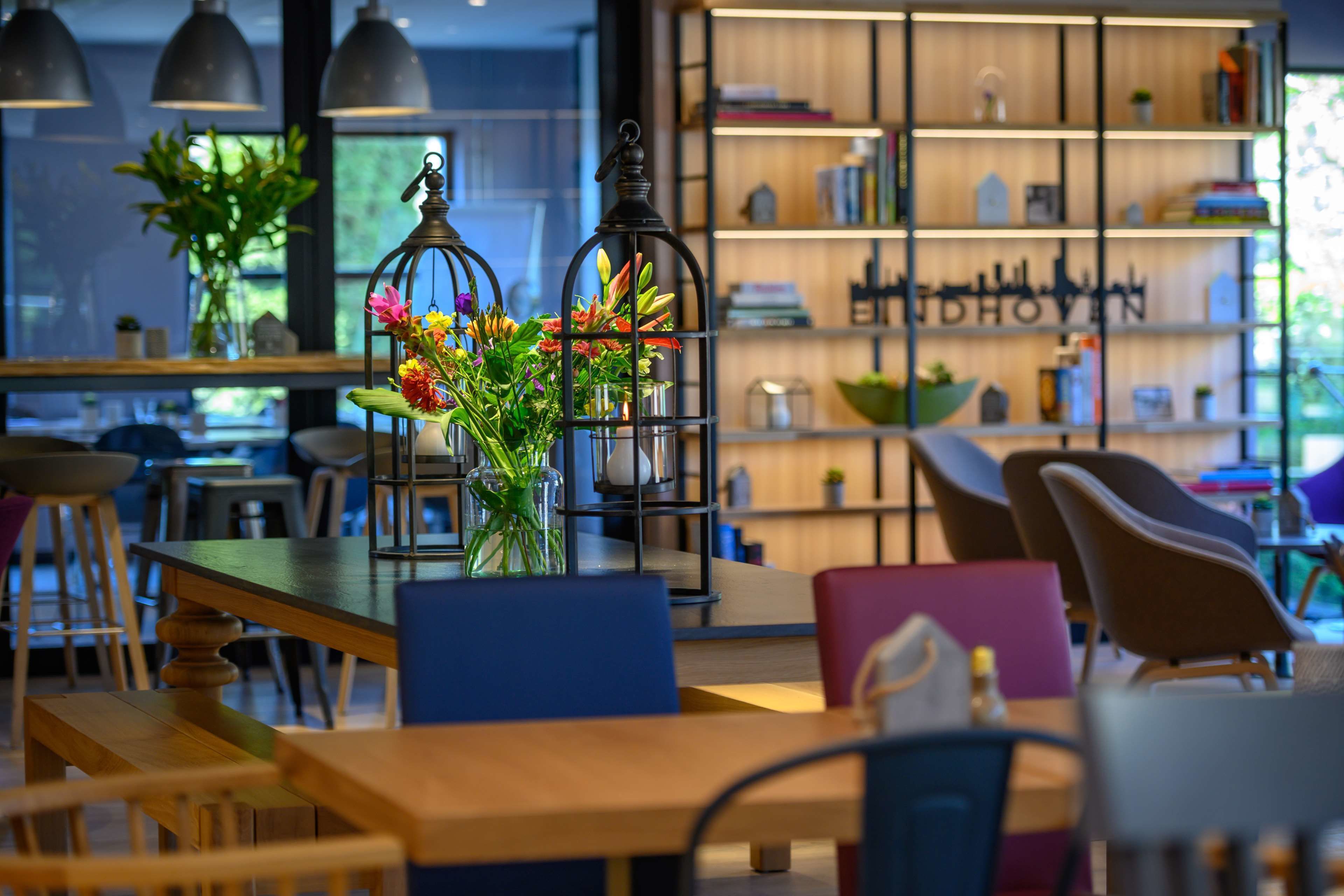 A modern interior with a wooden table, chairs, and a bookshelf with decorative items.