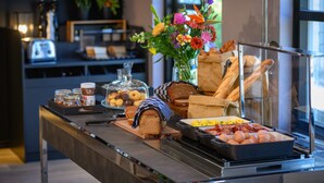 Un buffet de petit-déjeuner comprenant du pain, des viennoiseries, des œufs et une variété de tartinades.