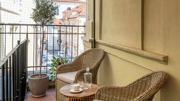 A balcony with wicker furniture, a potted plant, and a view of buildings.