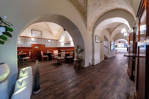 Una hall d'albergo con pavimento in legno, soffitti a volta e un'area salotto con tavoli e sedie.