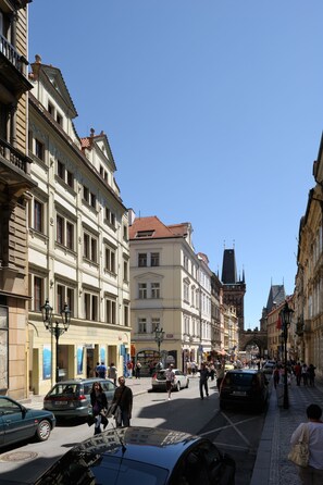 A street with historic buildings, a clear blue sky, and pedestrians.