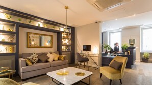 Una sala de estar moderna con un sofá, sillones, una mesa de centro y un escritorio con una computadora.