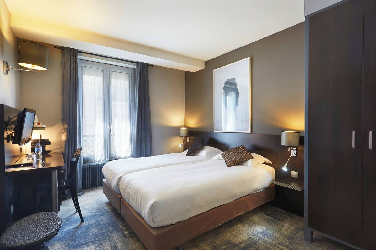 Une chambre d’hôtel avec un lit double, un bureau avec une chaise, une lampe et une grande œuvre d’art accrochée au mur.