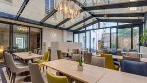 Un comedor moderno, con paredes de vidrio, varias mesas y sillas.