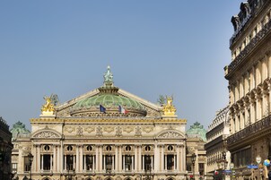A grand building with ornate architecture, featuring a prominent dome and statues on the roof.