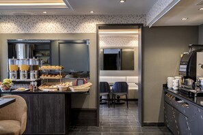Een moderne hotellobby met een receptiebalie, een zithoek en een buffet met diverse gerechten.