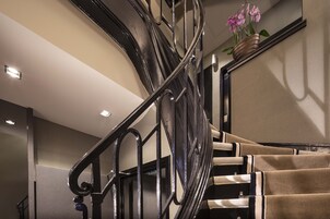 A spiral staircase with a black metal railing and beige carpeted steps.