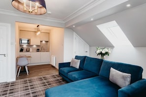 A modern apartment with a blue sofa, a kitchen, and a skylight. - Udny Arms Hotel (Ellon)