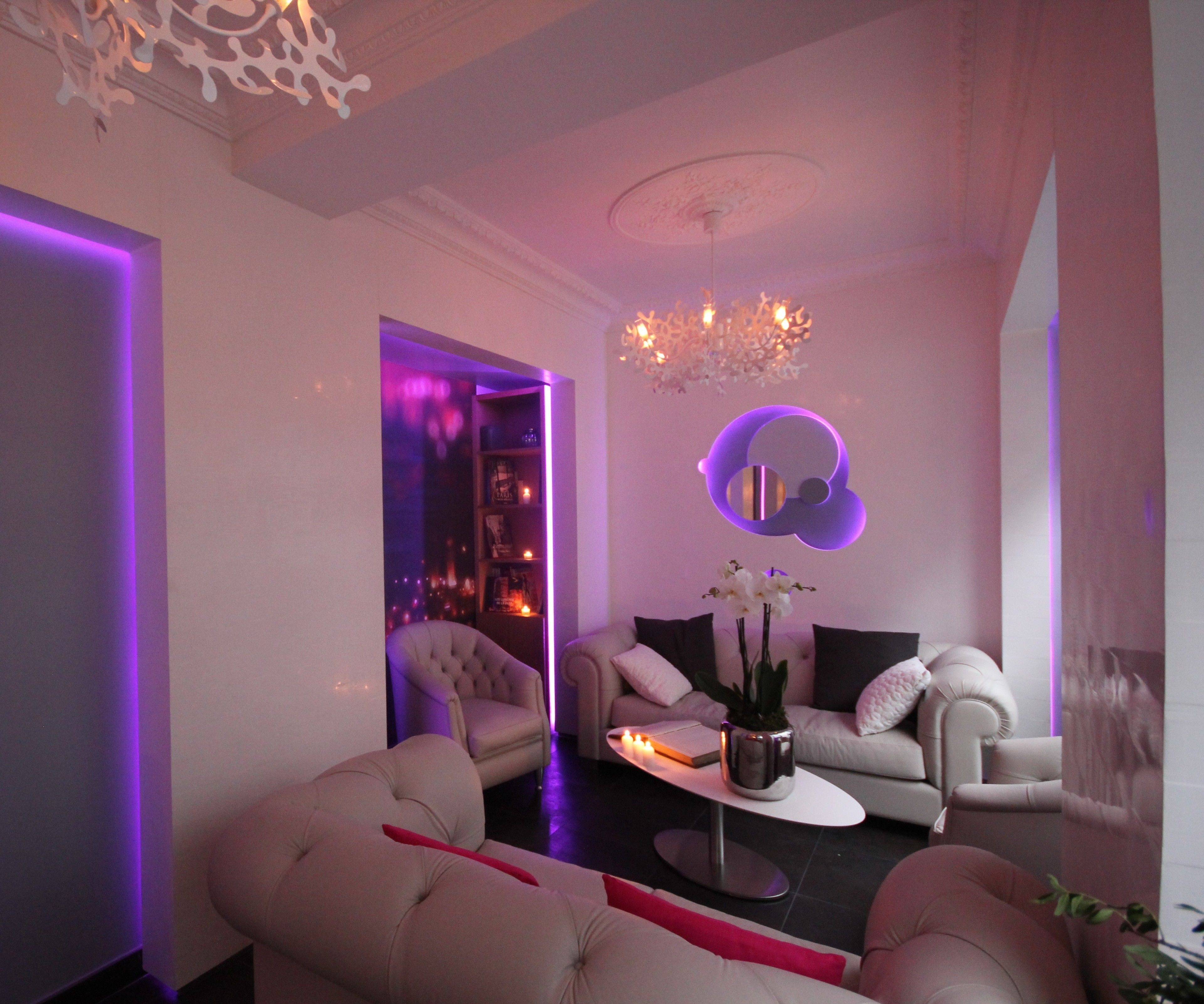 A modern living room with a sofa, armchairs, a coffee table, and a chandelier.