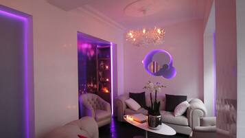 A modern living room with a sofa, armchairs, a coffee table, and a chandelier.