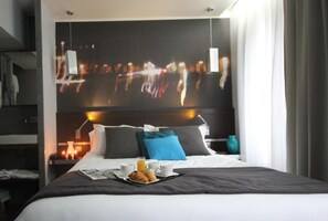 Une chambre d’hôtel avec un lit, un plateau de petit-déjeuner et un téléviseur fixé au mur qui diffuse des images d’un paysage urbain.