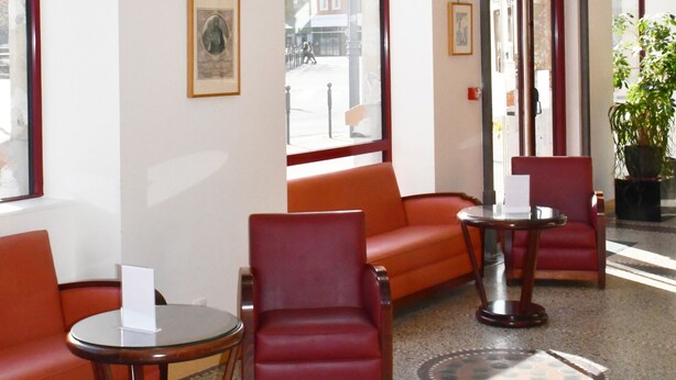A hotel lobby with seating, a reception desk, and large windows. - Hôtel Moderne (Arras)