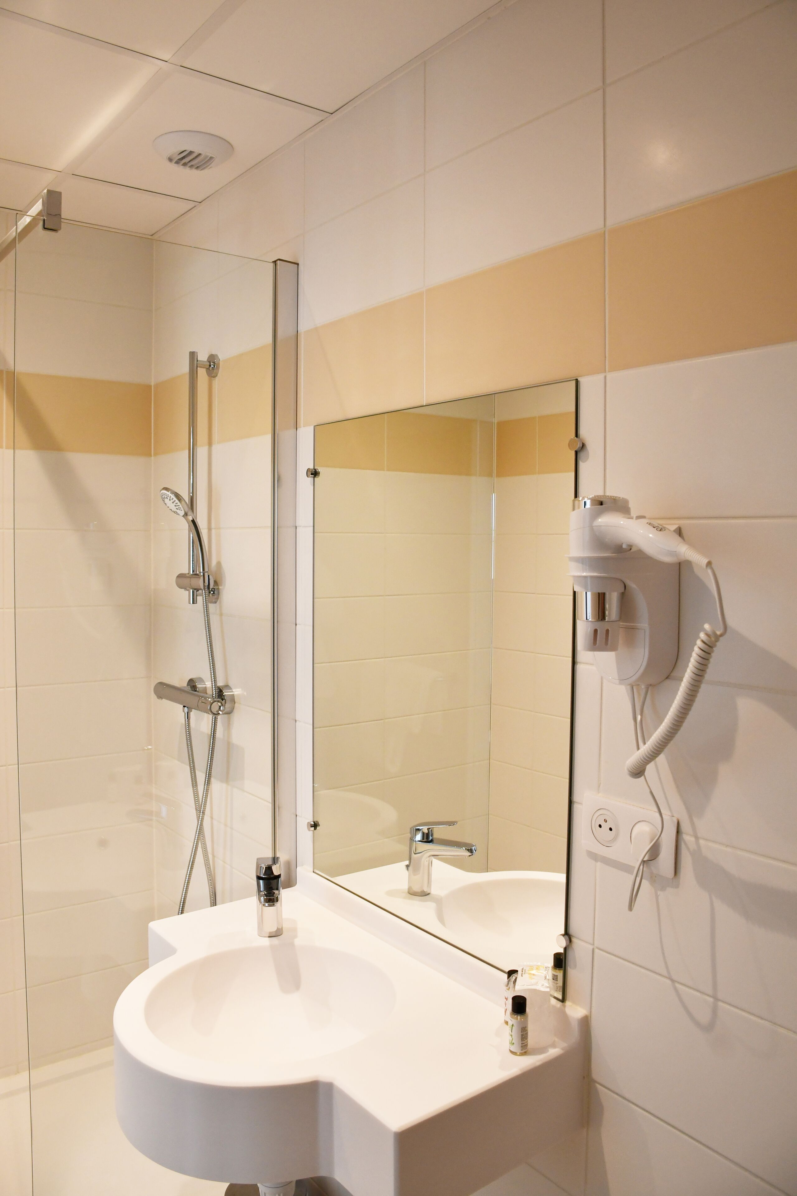 A modern bathroom with a glass-enclosed shower, a large mirror, and a built-in sink.