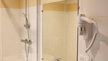 A modern bathroom with a glass-enclosed shower, a large mirror, and a built-in sink.