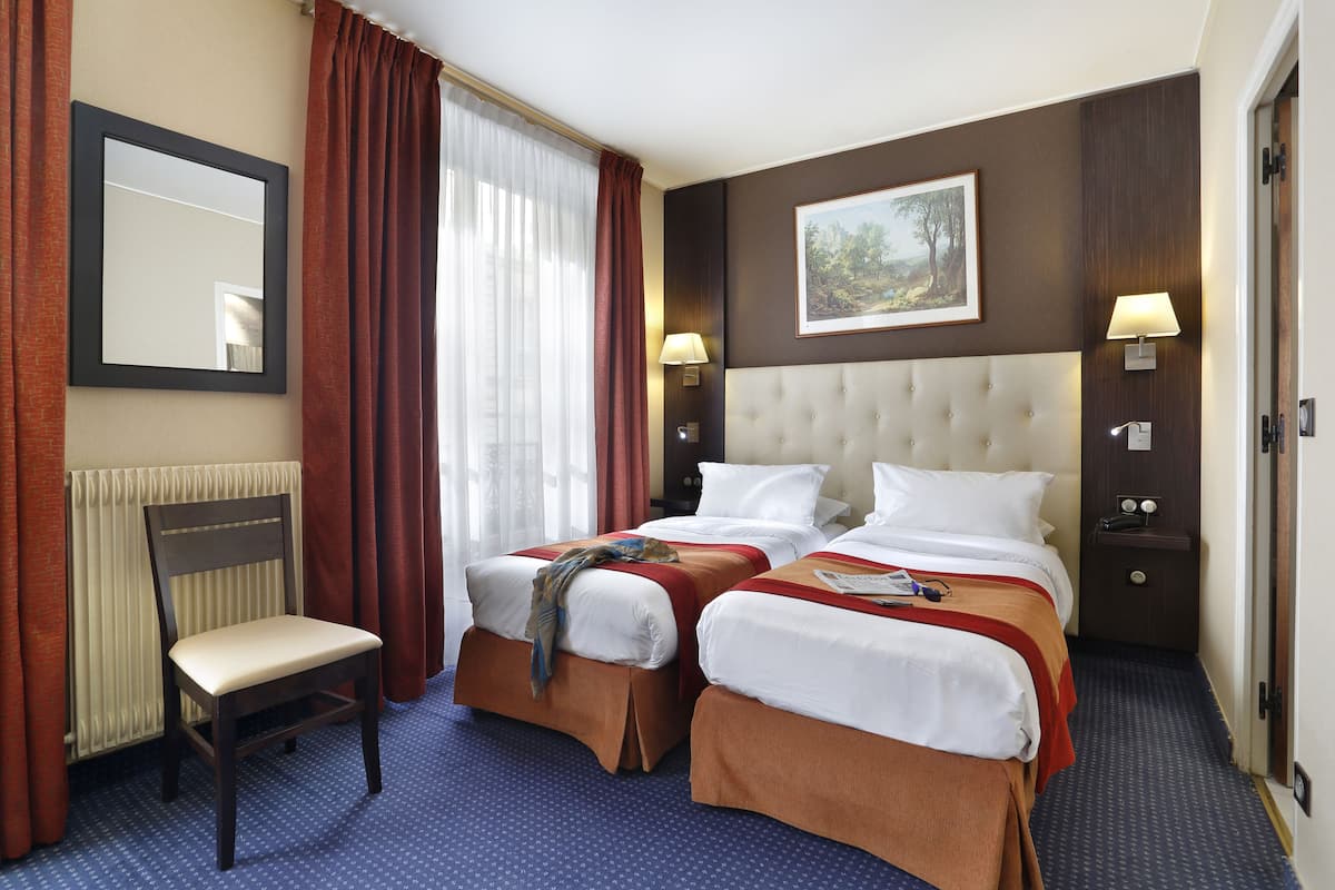 Een hotelkamer met twee bedden, een stoel, een grote spiegel en een schilderij aan de muur.