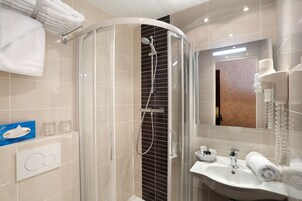 Un bagno moderno con doccia vetrata, lavabo con specchio e porta asciugamani.