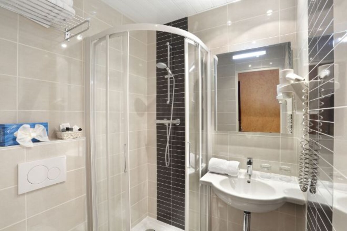A modern bathroom with a curved shower enclosure, a sink with a mirror, and a towel rack.