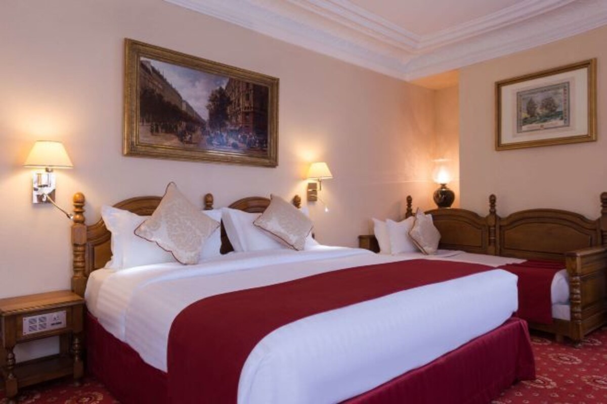 A hotel room with a large bed, two bedside tables, wall-mounted lamps, and framed artwork.