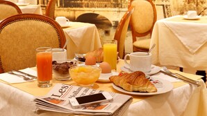 Ein Frühstückstisch mit Croissants, Orangensaft und Zeitungen, mit bekannten Sehenswürdigkeiten im Hintergrund.