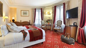 Ein Hotelzimmer mit einem großen Bett, einem Schreibtisch mit Stuhl, einem Fernseher und einem roten Teppichboden.