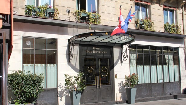 Ein Hotel mit Eingang, einer schwarzen Tür, einer Glaskuppel und einer Flagge.
