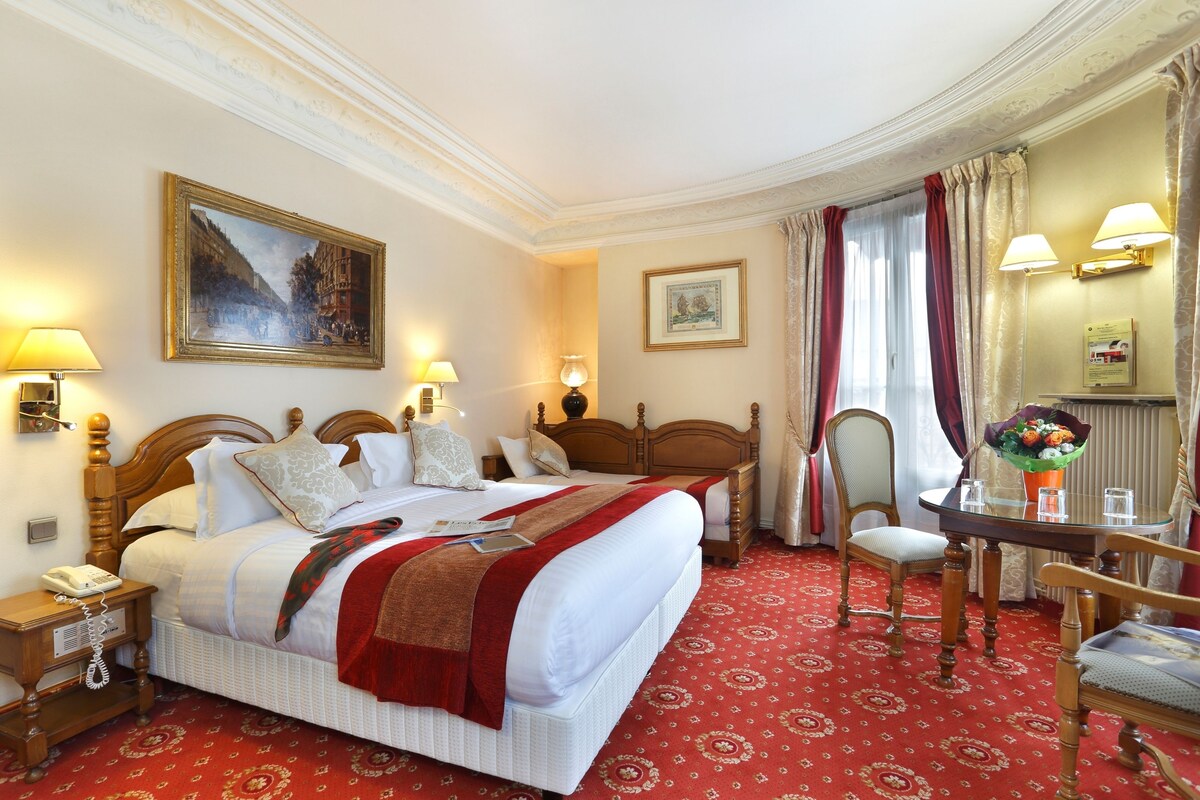 Une chambre d’hôtel avec un grand lit, deux tables de chevet, un bureau avec une chaise et un tableau au mur.