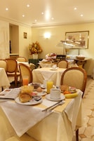 A breakfast setting with tables, chairs, and a variety of breakfast items including croissants, fruits, and beverages.