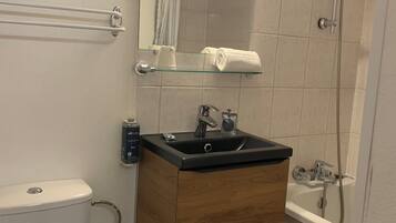 Een badkamer met toilet, wastafel, spiegel, handdoekhouder en douche.