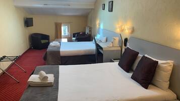 A hotel room with two beds, a desk, a chair, a TV, and a skylight.