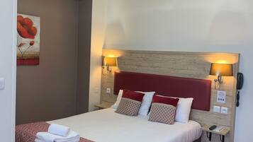 Habitación de hotel con cama, cabecera, dos lámparas de noche, mesita de noche y teléfono fijo en la pared.