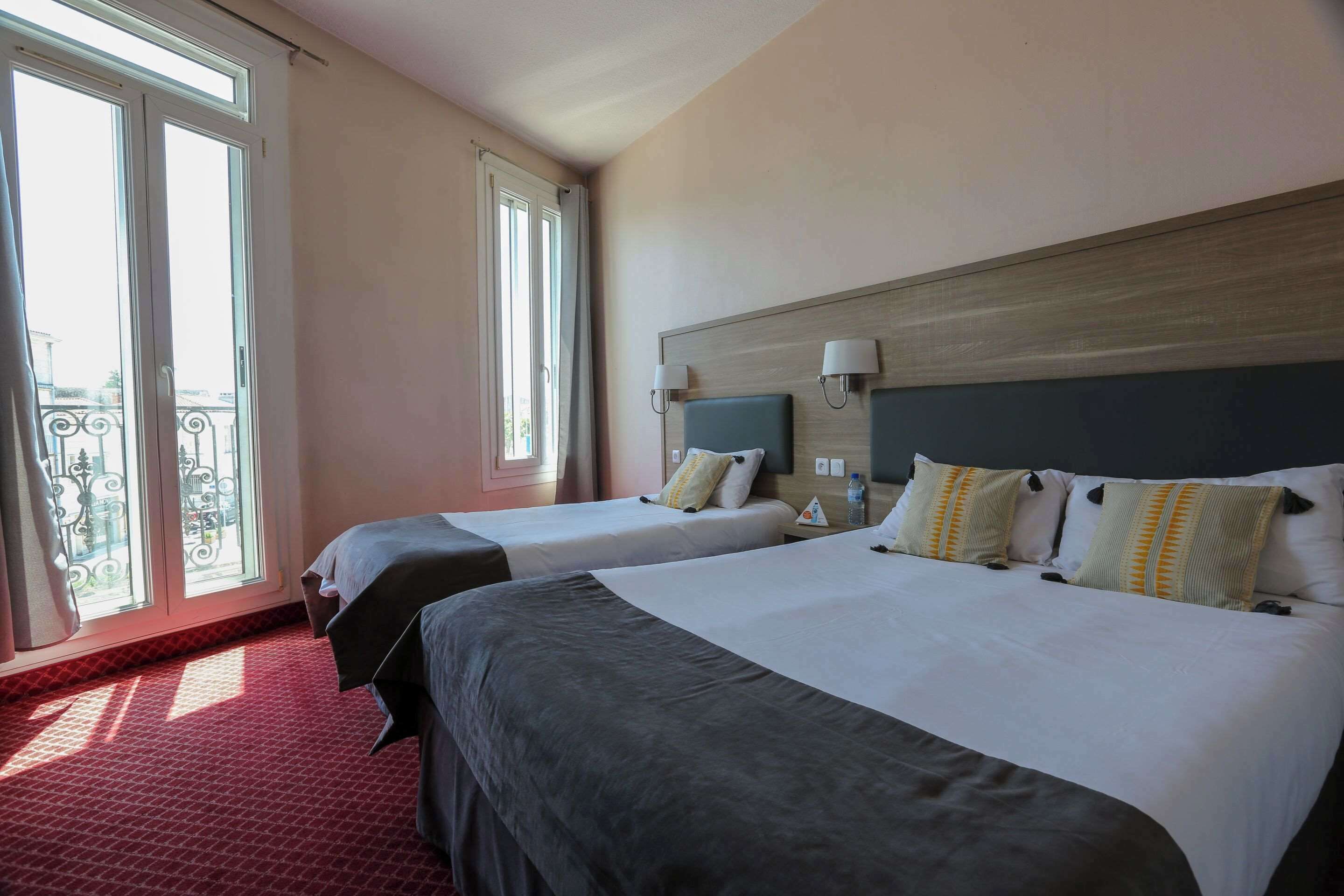 Quarto de hotel com duas camas, varanda e vista da cidade.