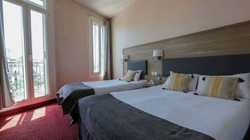 Quarto de hotel com duas camas, varanda e vista da cidade.