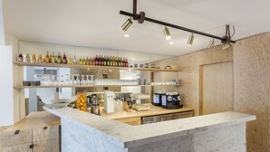 A modern kitchen with marble countertops, a coffee station, and a variety of bottles and glasses on shelves. - Hôtel Montholon Paris (Paris)