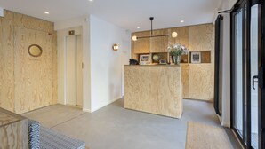 A reception area with a wooden reception desk, a globe, framed pictures, and a modern pendant light. - Hôtel Montholon Paris (Paris)