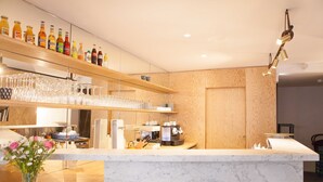 A modern kitchen with a marble countertop, wooden shelves with bottles, and a coffee machine. - Hôtel Montholon Paris (Paris)