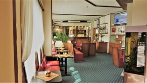 Un vestíbulo de hotel con zonas de estar, un bar y una pantalla de televisión.