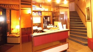 Zona de recepción con mostrador, escalera y puerta que da a otra habitación.