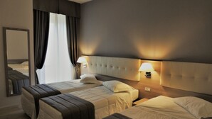 Habitación de hotel con dos camas, un espejo grande y dos lámparas fijadas a la pared.