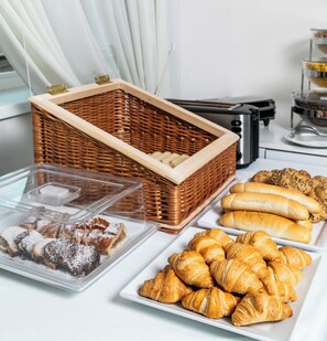 A buffet table with various baked goods including bread, pastries, and a wicker basket. - My Hotel Apollon Prague (Prague)