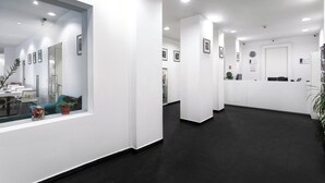 Una zona de recepción moderna con piso oscuro, paredes blancas y un amplio ventanal.