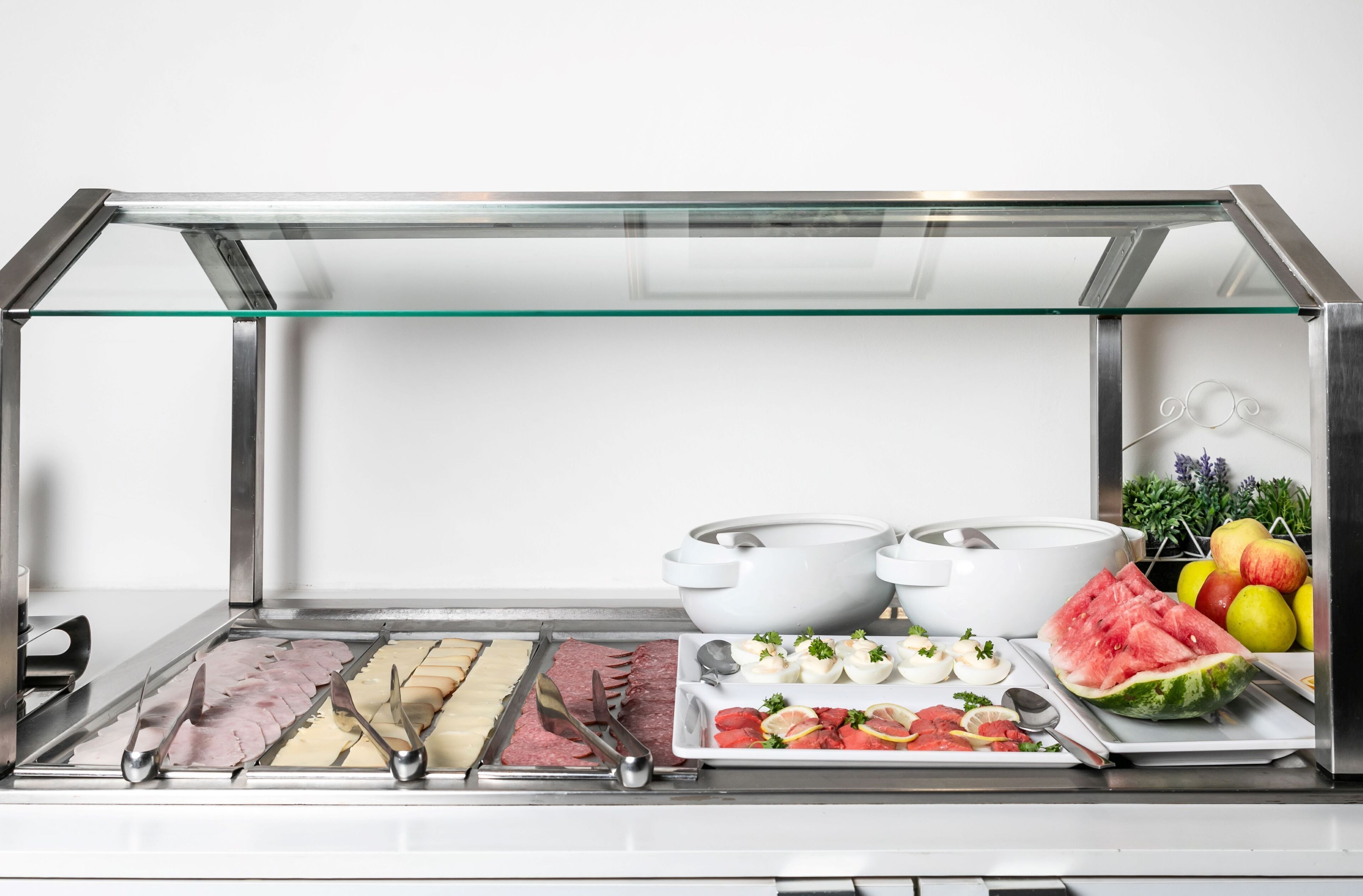En buffet med forskellige retter, herunder kød, æg og frugt.