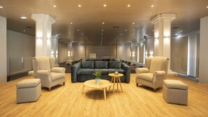 Un amplio salón con un sofá grande de color gris, dos sillones, una mesita de centro redonda y una pequeña mesa auxiliar.