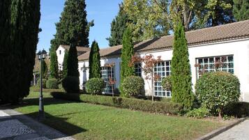 A building with a tiled roof, surrounded by well-maintained hedges and tall trees.